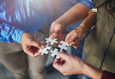 Buy stock photo Shot of a team of businesspeople putting puzzle pieces together in an office