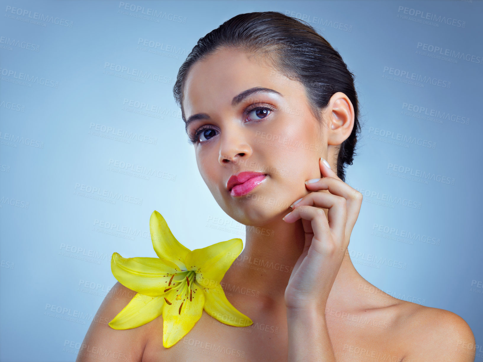 Buy stock photo Beauty, woman and thinking with lily in studio for natural product, organic skincare and vegan cosmetics. Flower, calm or female person on blue background for wellness, peace or healthy spa treatment