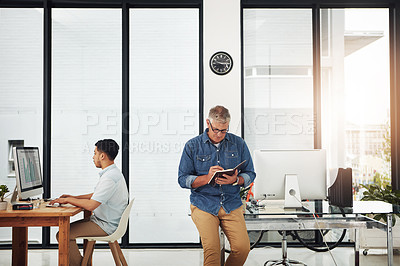 Buy stock photo Shot of two male designers working individually in their office
