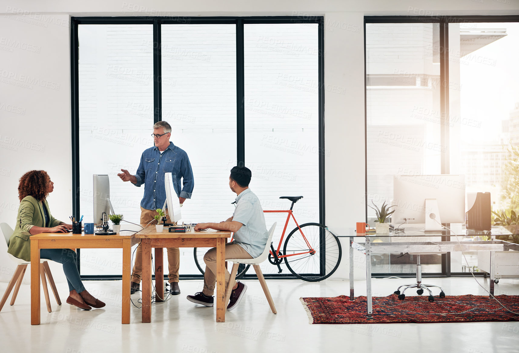 Buy stock photo Shot of a mature businessman addressing two employees in the office