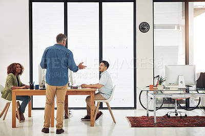 Buy stock photo Shot of a mature businessman addressing two employees in the office