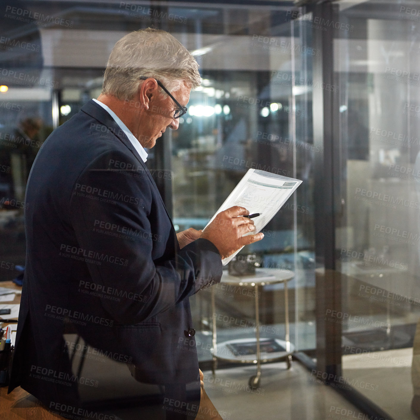 Buy stock photo Shot of a dedicated businessman working alone in his office after hours