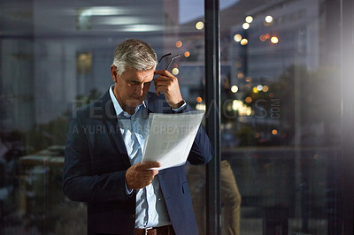Buy stock photo Shot of a dedicated businessman working alone in his office after hours