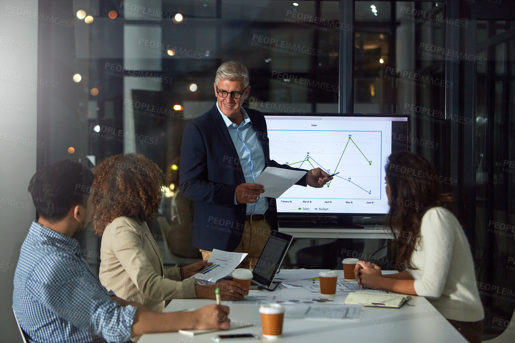 Buy stock photo Shot of a dedicated businessman giving a presentation to his colleagues in the boardroom after hours