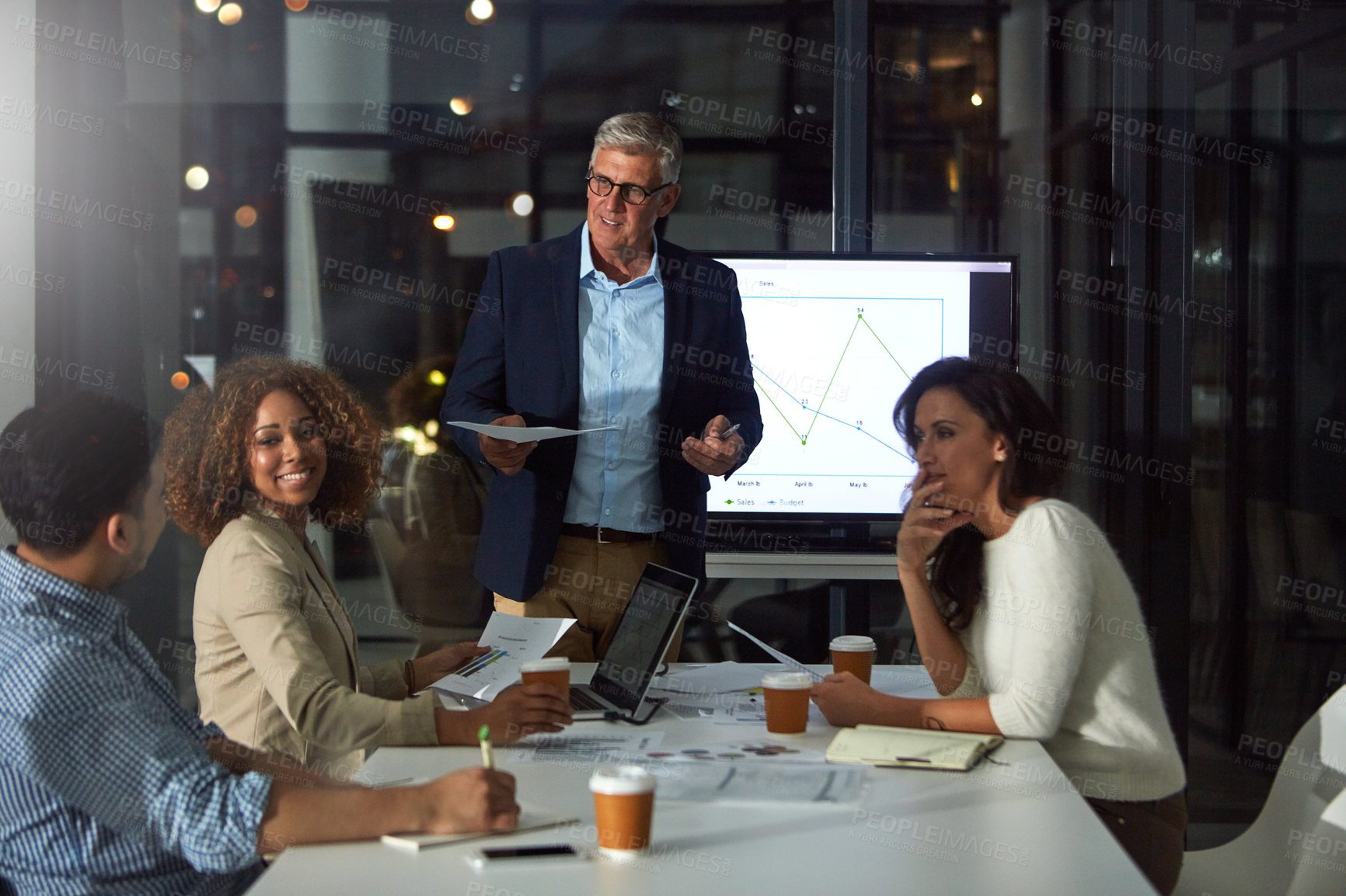 Buy stock photo Shot of a dedicated businessman giving a presentation to his colleagues in the boardroom after hours