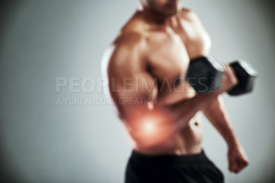 Buy stock photo Shot of a sporty young man working out with a dumbbell against a grey background