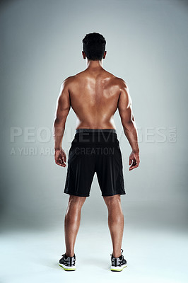 Buy stock photo Rearview shot of a sporty young man standing against a grey background