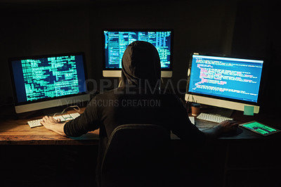 Buy stock photo Rearview shot of a young hacker cracking a computer code in the dark