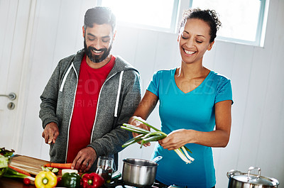 Buy stock photo Shot of a happy couple cooking together in their kitchen at home