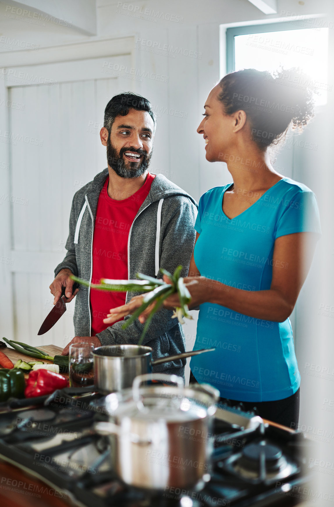 Buy stock photo Shot of a happy couple cooking together in their kitchen at home