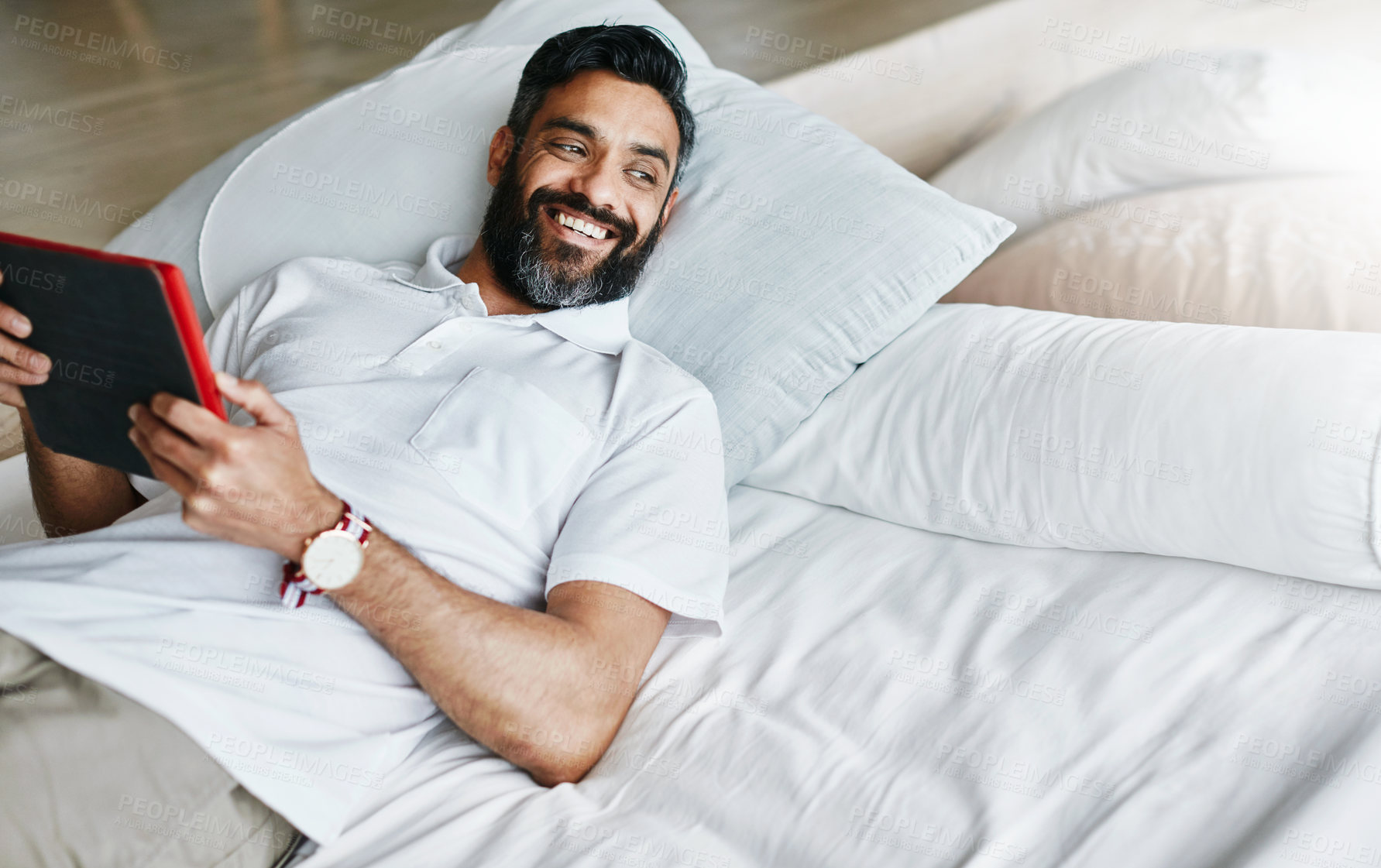 Buy stock photo Shot of a easygoing bachelor using his tablet while relaxing on the couch at home