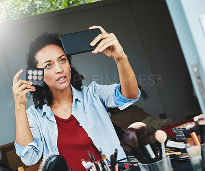 Buy stock photo Shot of a woman posing for a selfie with a makeup palette at home