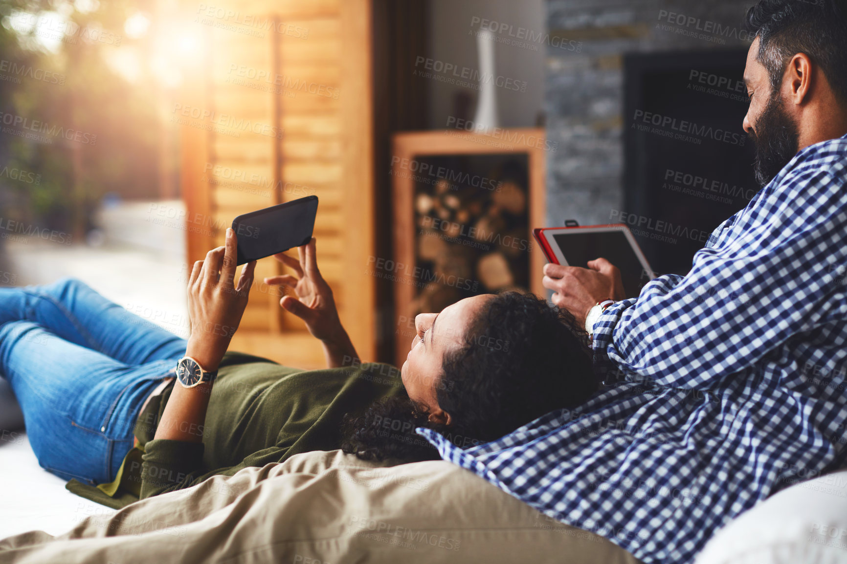 Buy stock photo Shot of a laid-back couple relaxing with wireless technology at home