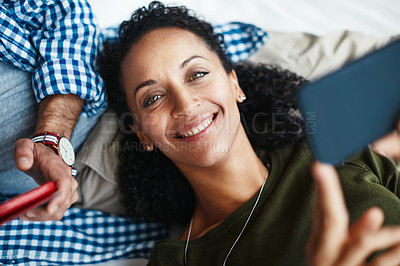 Buy stock photo Portrait of a happy woman using her smartphone while relaxing at home with her husband