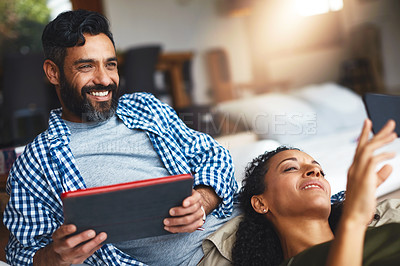 Buy stock photo Shot of a laid-back couple relaxing with wireless technology at home