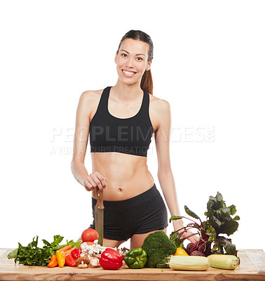 Buy stock photo Studio portrait of an attractive young woman posing with a table full of vegetables against a white background