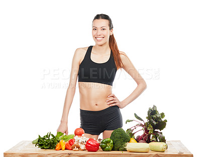 Buy stock photo Studio portrait of an attractive young woman posing with a table full of vegetables against a white background