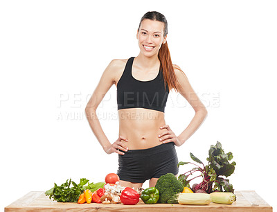 Buy stock photo Studio portrait of an attractive young woman posing with a table full of vegetables against a white background