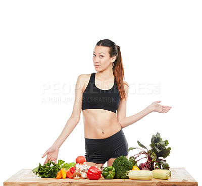 Buy stock photo Studio portrait of an attractive young woman posing with a table full of vegetables against a white background