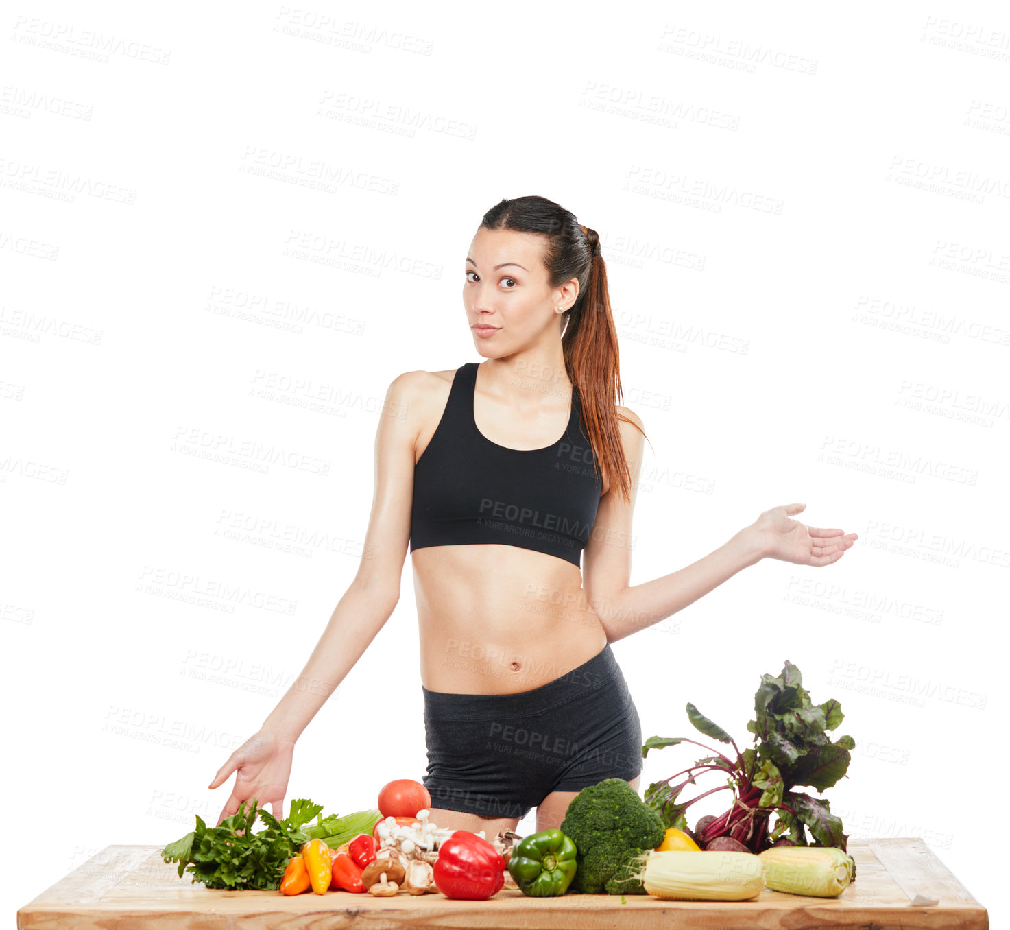 Buy stock photo Studio portrait of an attractive young woman posing with a table full of vegetables against a white background