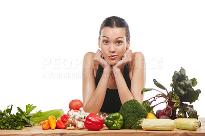 Buy stock photo Studio portrait of an attractive young woman posing with a table full of vegetables against a white background