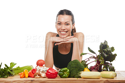 Buy stock photo Studio portrait of an attractive young woman posing with a table full of vegetables against a white background