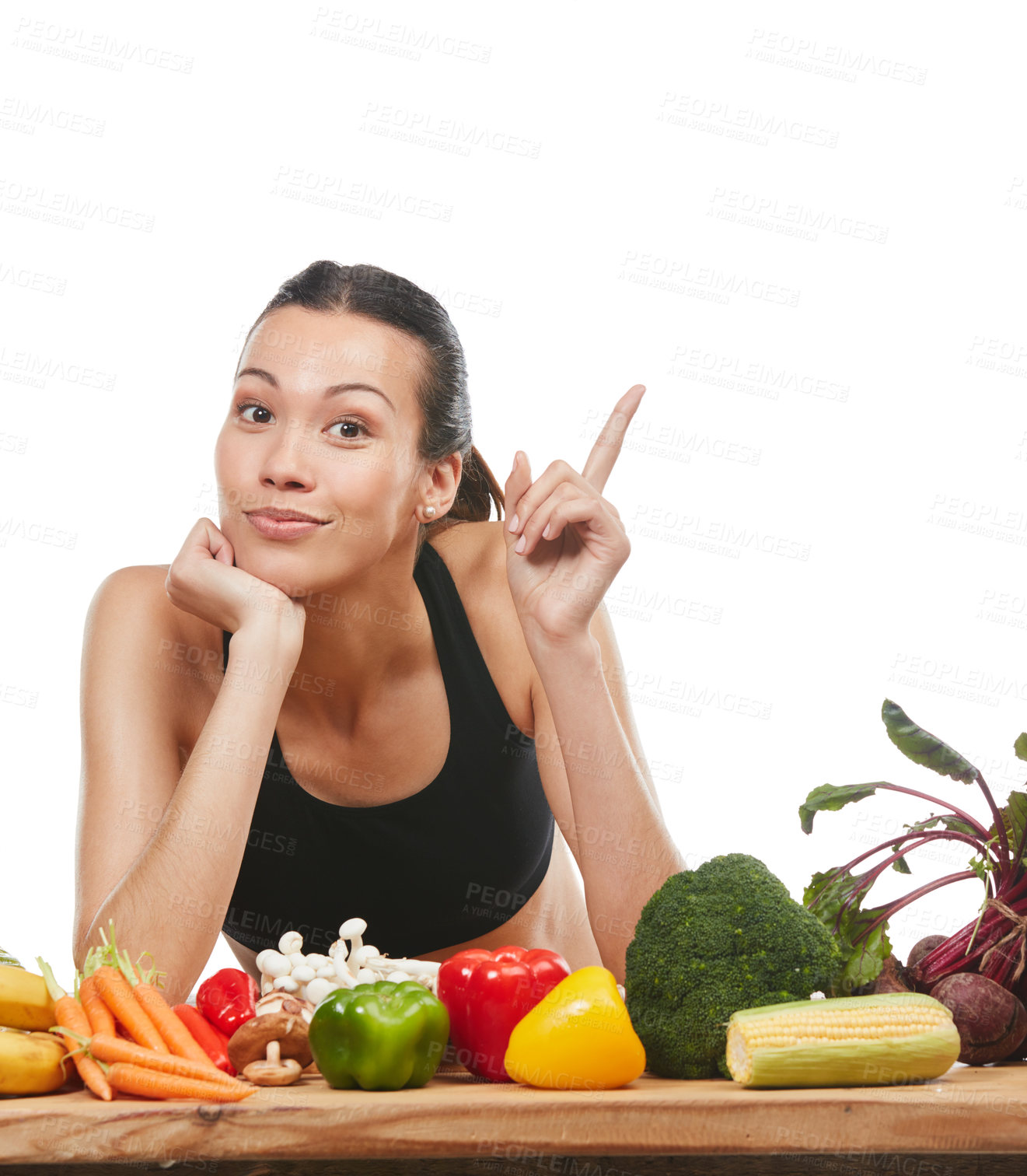 Buy stock photo Studio portrait of an attractive young woman posing with a table full of vegetables against a white background