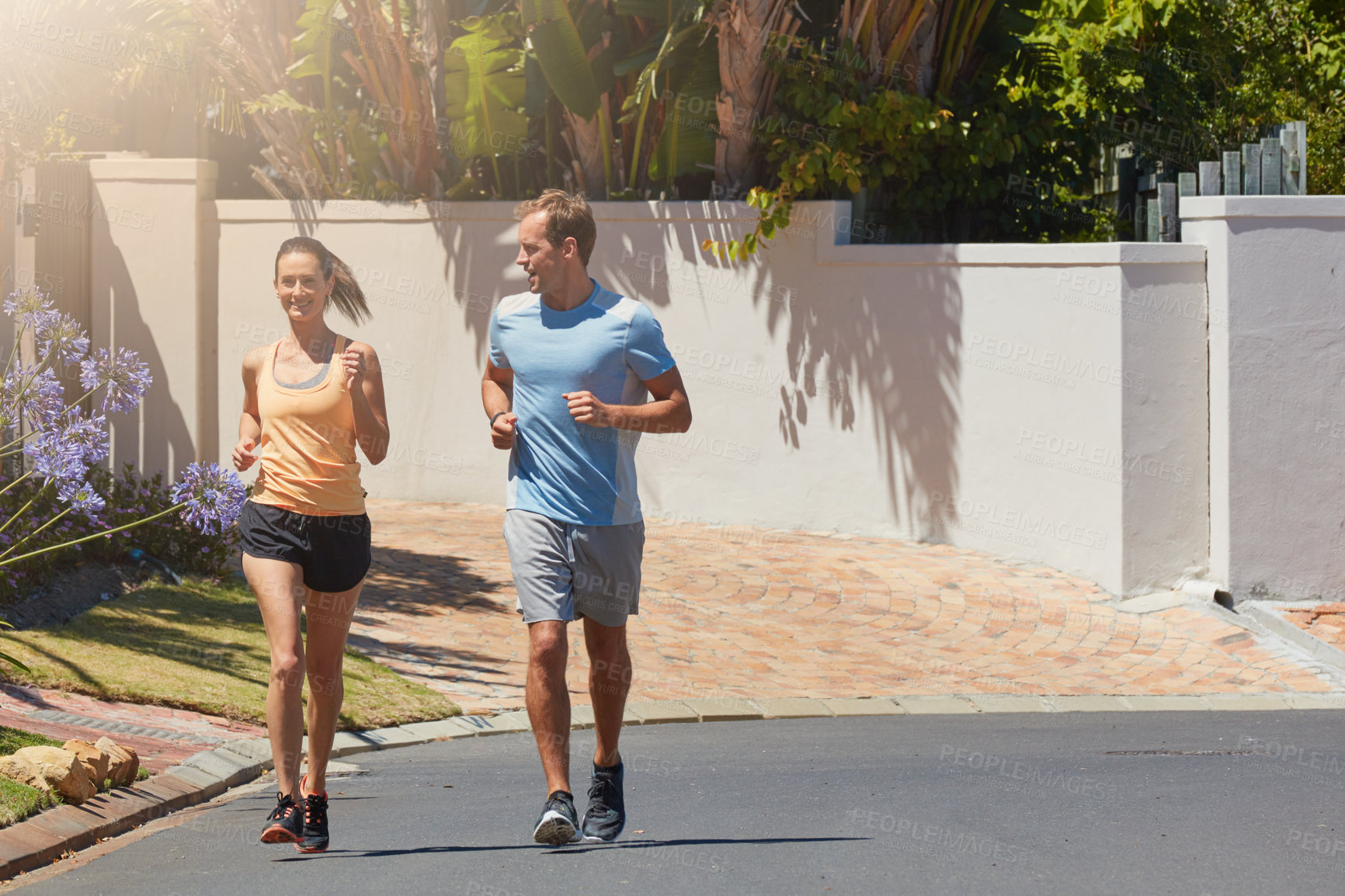 Buy stock photo Shot of a happy couple jogging together in their neighborhood