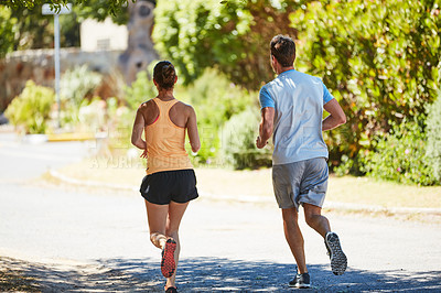 Buy stock photo Rearview shot of an unidentifiable couple jogging together in their neighborhood