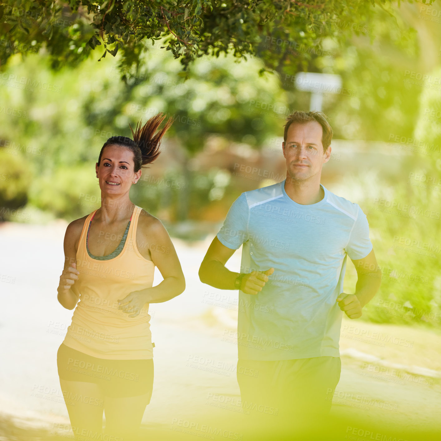 Buy stock photo Shot of a happy couple jogging together in their neighborhood