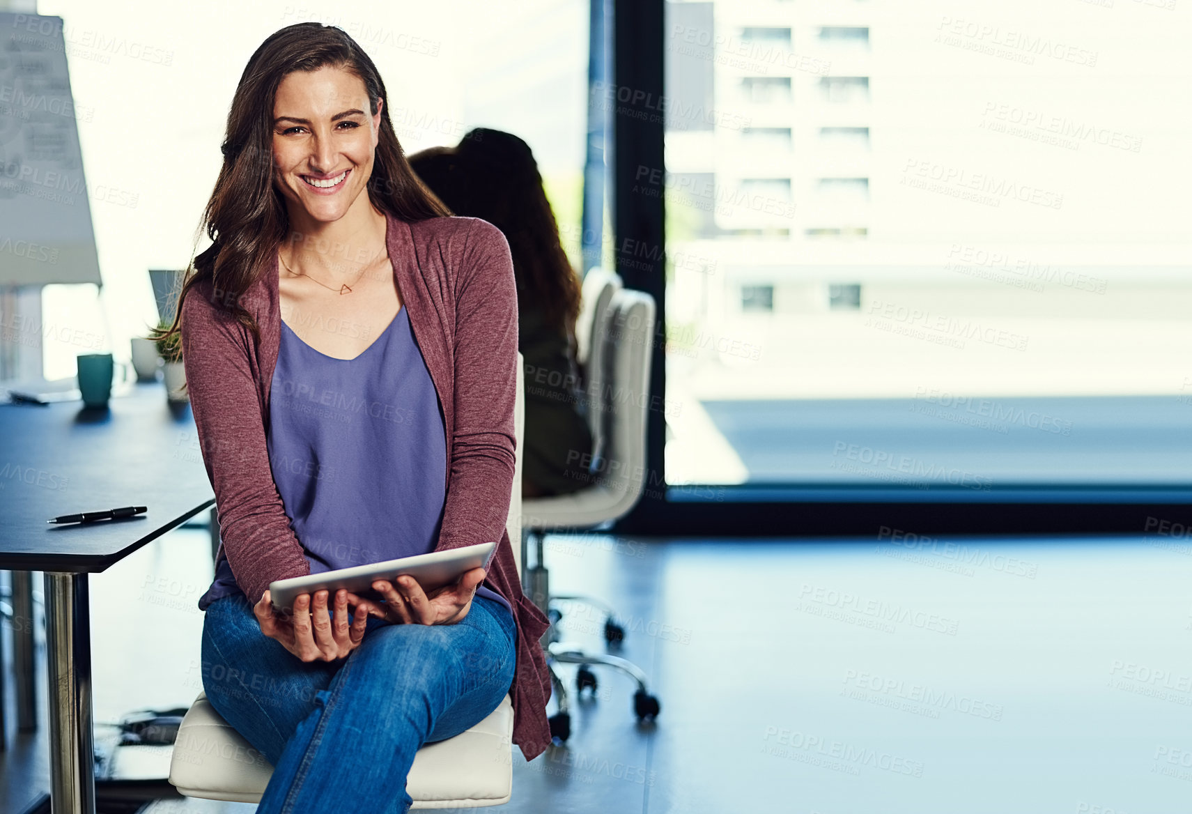 Buy stock photo Portrait of a young businesswoman working on a digital tablet with her colleagues in the background