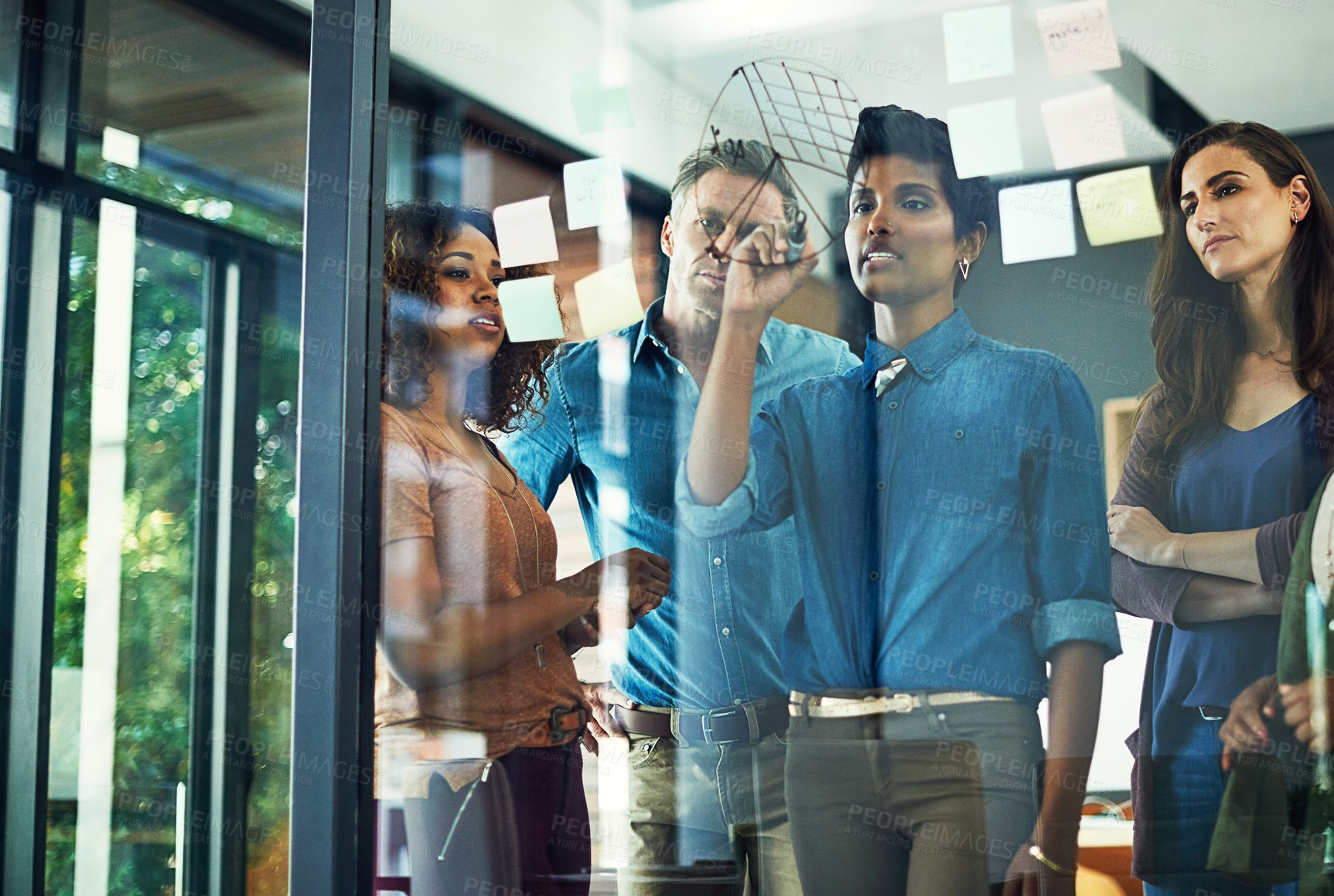 Buy stock photo Cropped shot of a group of businesspeople brainstorming with notes on a glass wall in an office