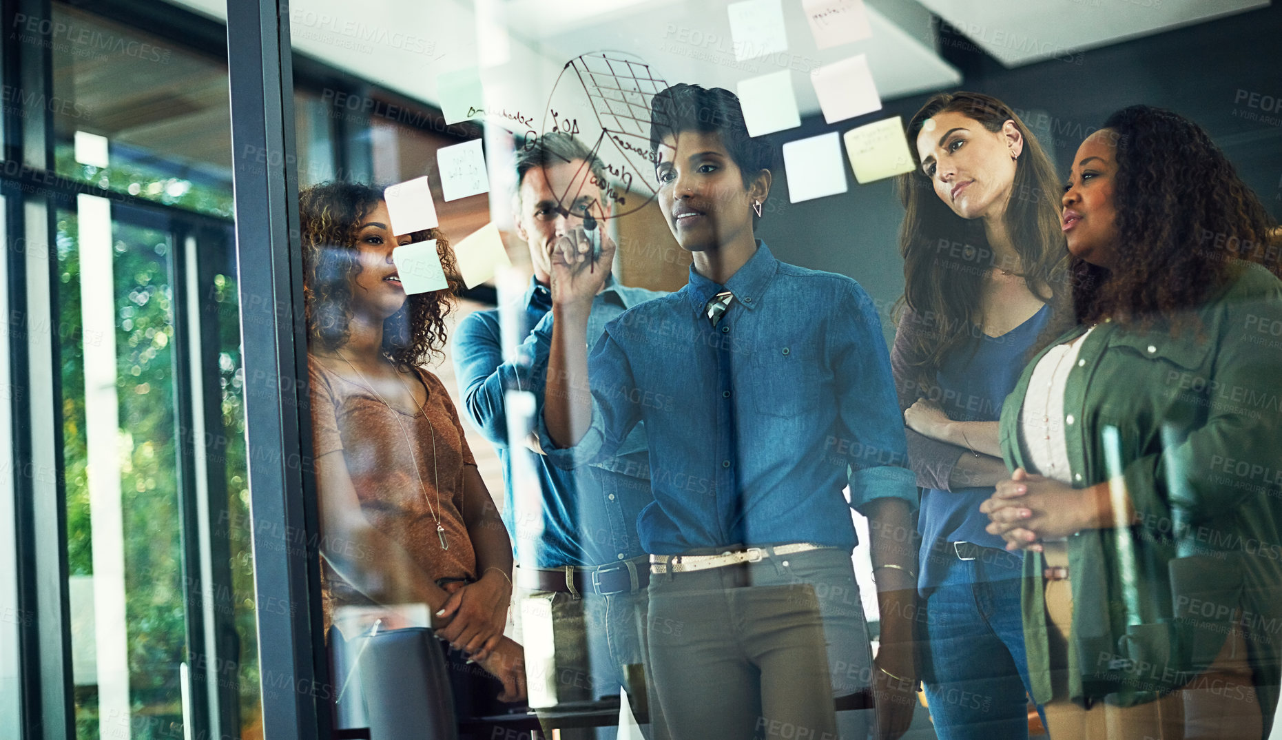 Buy stock photo Cropped shot of a group of businesspeople brainstorming with notes on a glass wall in an office