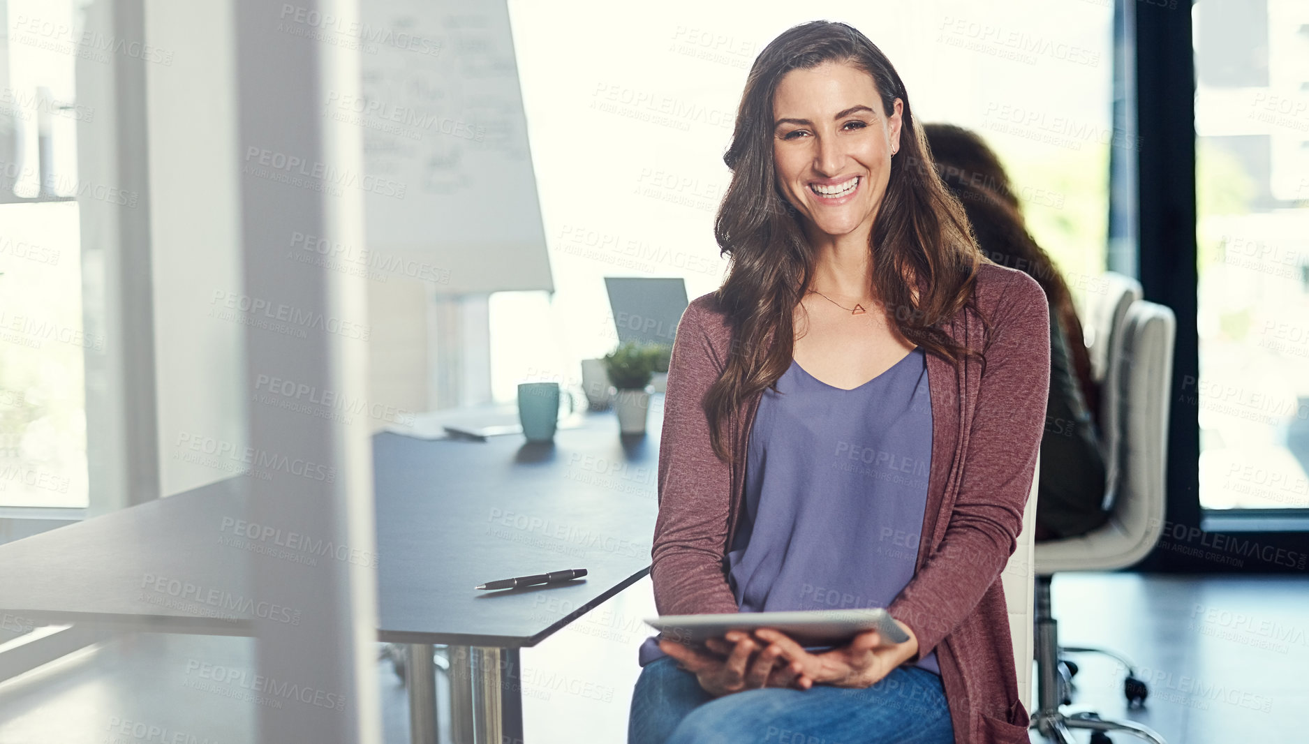 Buy stock photo Portrait of a young businesswoman working on a digital tablet with her colleagues in the background