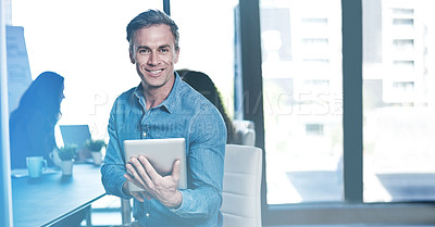 Buy stock photo Shot of a businessman using a digital tablet with his colleagues blurred in the background