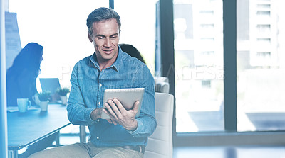 Buy stock photo Shot of a businessman using a digital tablet with his colleagues blurred in the background