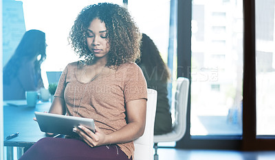 Buy stock photo Shot of a businesswoman using a digital tablet with her colleagues blurred in the background