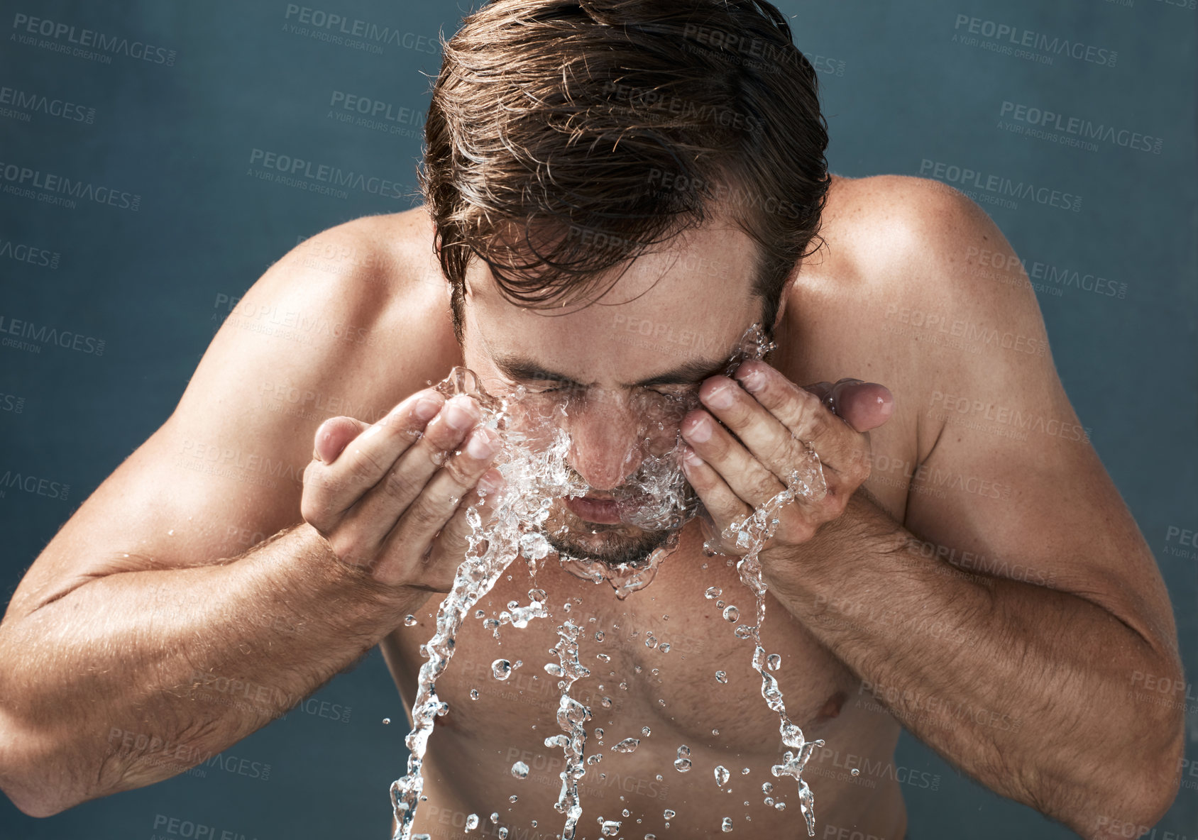 Buy stock photo Cropped shot of a young man washing his face against a grey background