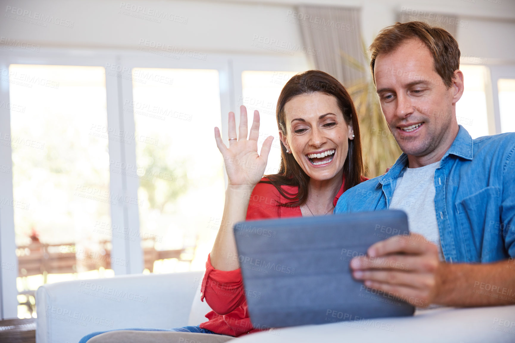 Buy stock photo Shot of a mature couple making a video call together on a digital tablet at home