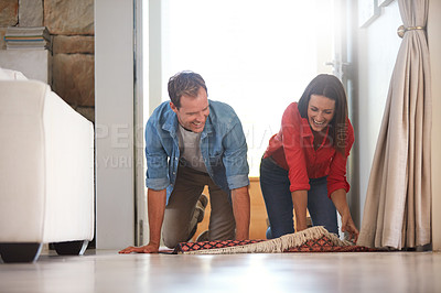Buy stock photo Shot of a mature couple rolling out a carpet together at home