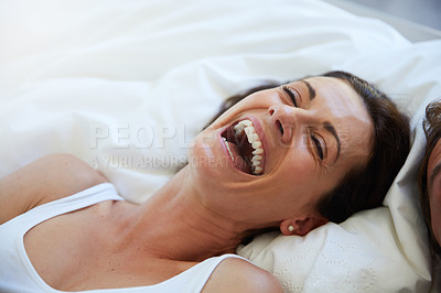 Buy stock photo Shot of a woman laughing while relaxing in bed alongside her husband