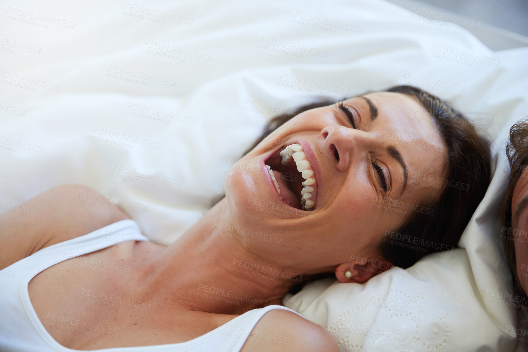 Buy stock photo Shot of a woman laughing while relaxing in bed alongside her husband