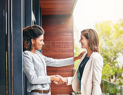 Buy stock photo Shot of two businesswomen shaking hands outside an office