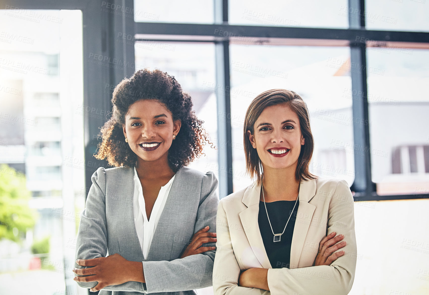 Buy stock photo Portrait of two confident young businesswomen standing together in an office