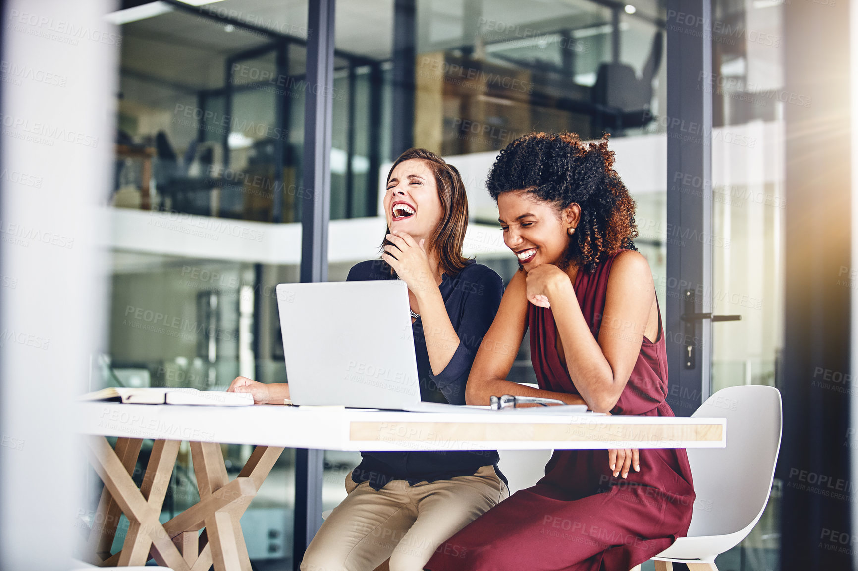 Buy stock photo Cropped shot of two young businesswomen using a laptop in an office