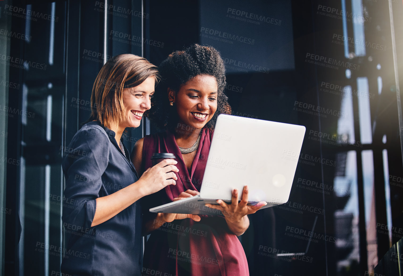 Buy stock photo Cropped shot of two young businesswomen using a laptop outside an office