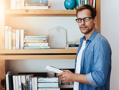 Buy stock photo Cropped portrait of a handsome man getting a book from his bookshelf