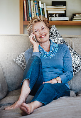 Buy stock photo Shot of a relaxed senior woman using a phone at home on the sofa