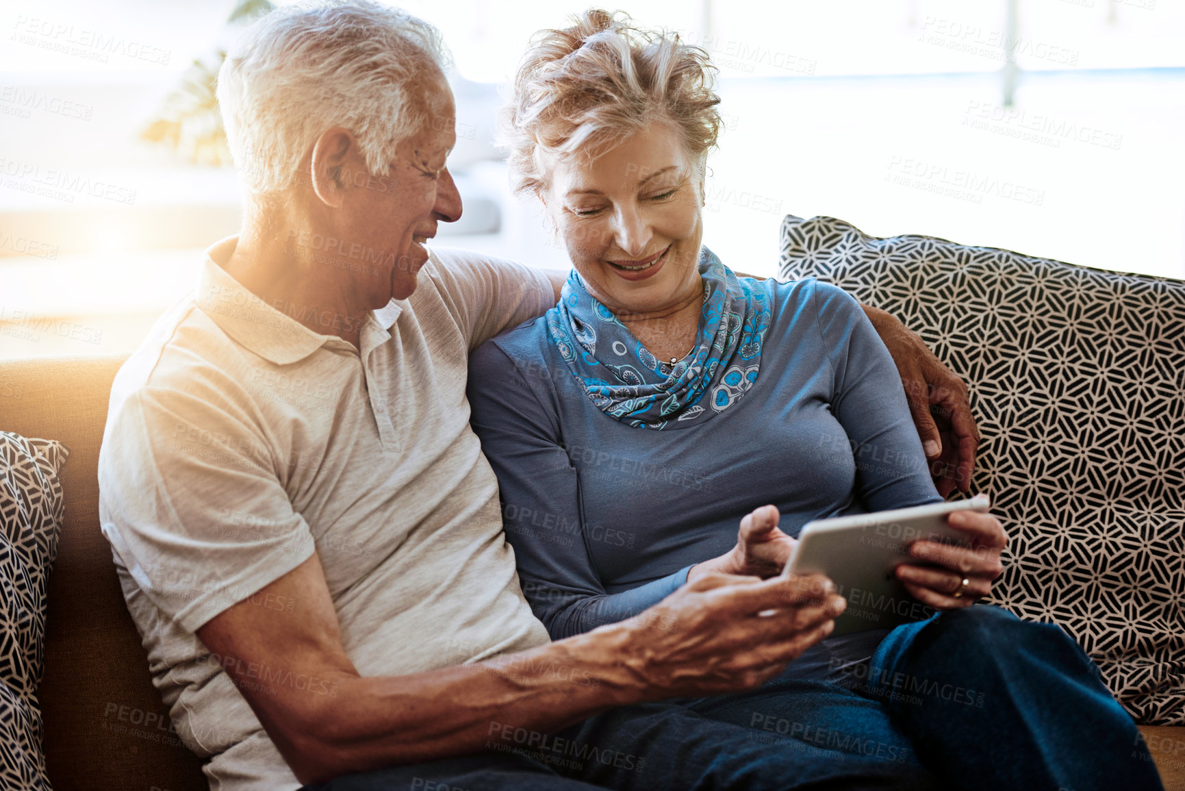 Buy stock photo Shot of a happy senior couple using a digital tablet together on the sofa at home