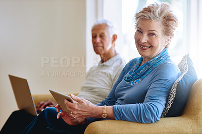 Buy stock photo Portrait of a senior woman using a digital tablet while her husband uses a laptop on the sofa at home